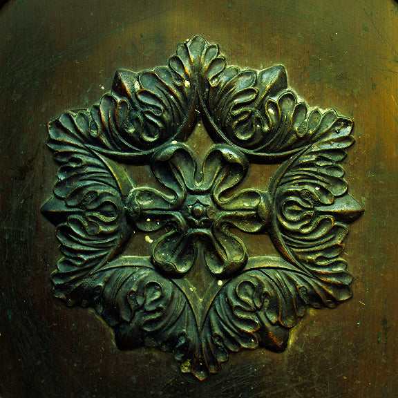 Ornate metal decoration with symmetrical leaf and floral patterns in a star-shaped arrangement.