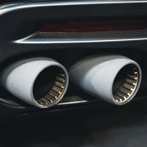 Close-up of dual exhaust pipes on a dark-colored vehicle.