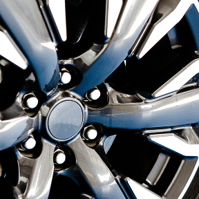 Close-up of a shiny metallic car wheel rim with multiple spokes and lug nut holes.