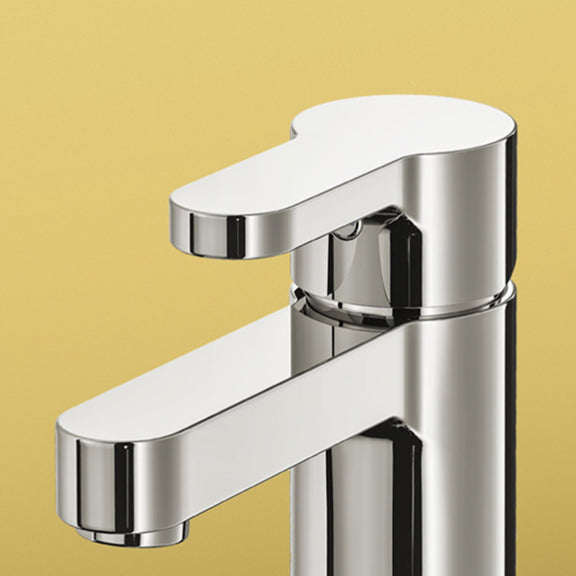 Chrome single-handle bathroom faucet with a flat lever and spout against a yellow background.