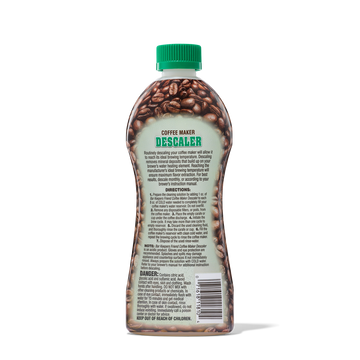 Bottle of coffee maker descaler with instructions and warnings on the label, featuring coffee beans design and a green cap.