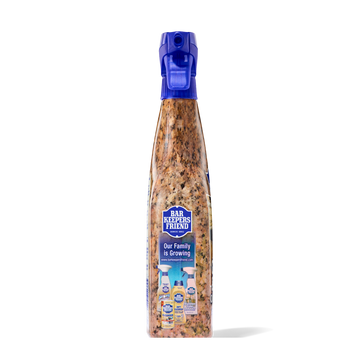 Spray bottle with blue nozzle containing granite and stone cleaner and polish with speckled brown liquid inside.