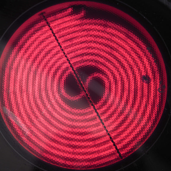 Red glowing electric stovetop burner with a spiral coil design and a black line across the center.