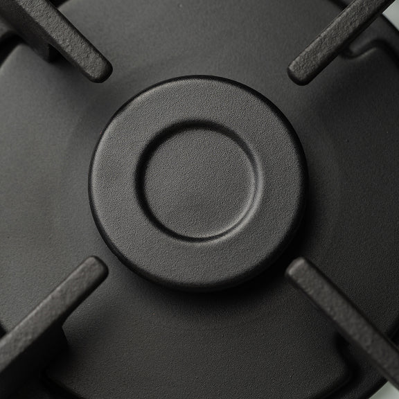 Close-up of a black gas stove burner with four metal supports surrounding the central burner cap.